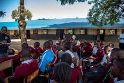 A facilitator speaking to a large group of students outdoors.